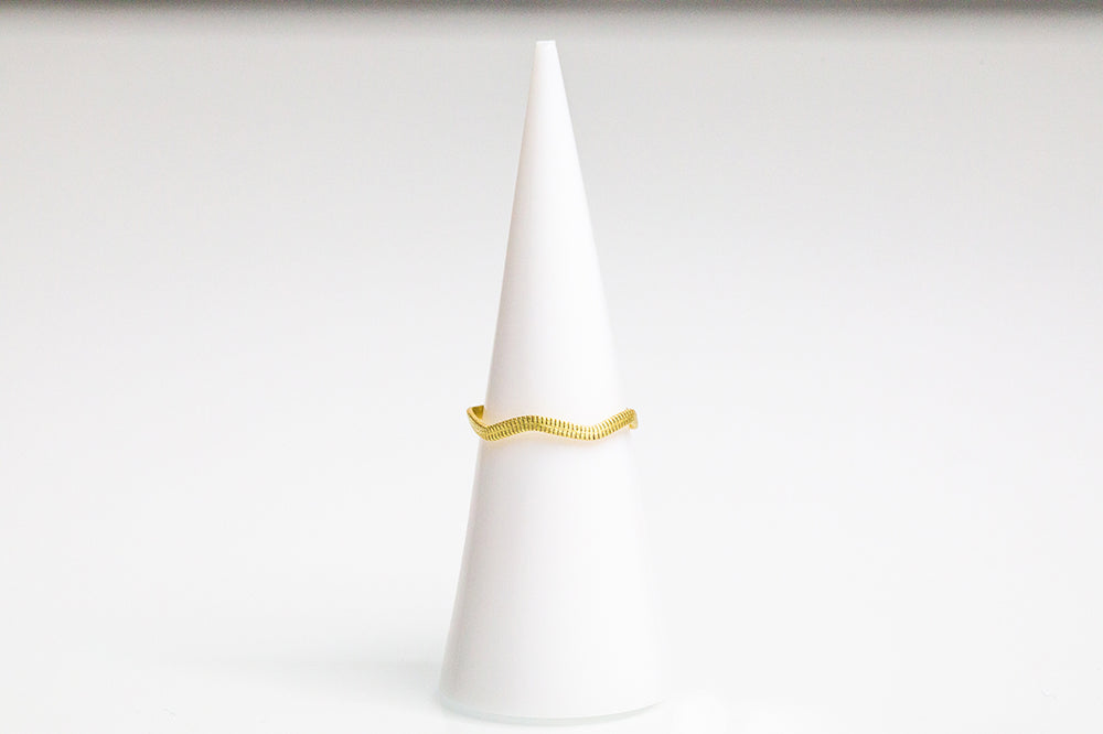 A flattened guitar string ring. Plated in 14k gold, wavy shape, string texture. 